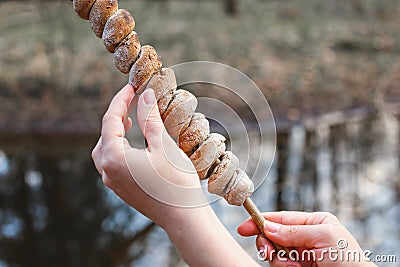 Dough on a stick cooked on a fire in the forest in the hands of a girl Stock Photo