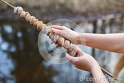 Dough on a stick cooked on a fire in the forest in the hands of a girl Stock Photo