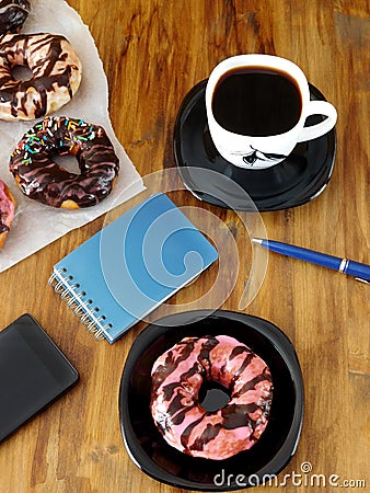 Doughnut, cup of coffee and stationery on a wooden table Stock Photo