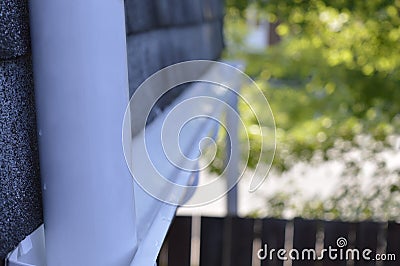 A down spout pipe leading to an eavestrough installed below a roof ledge. Stock Photo