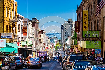 Downtown city life in a busy street of Chinatown San Francisco. View with many people, shops and cars - lookout to the Oakland Bay Editorial Stock Photo
