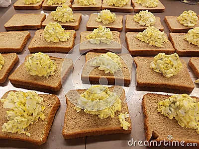 Dozens of egg salad sandwiches on metal table at the soup kitchen, feeding the hungry Stock Photo