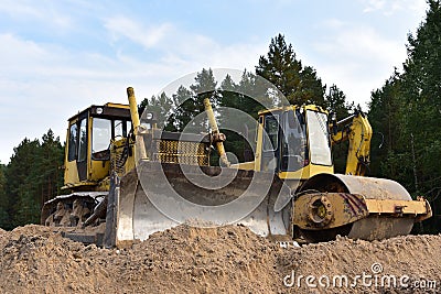 Dozer and Vibro Roller Soil Compactor at road construction and bridge projects in forest area. Heavy machinery for road work. Stock Photo