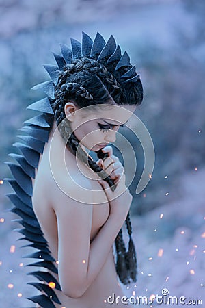 Dragon girl Black, sharp thorns cover the back and head of a young woman. Creative fabulous image of an alien humanoid Stock Photo