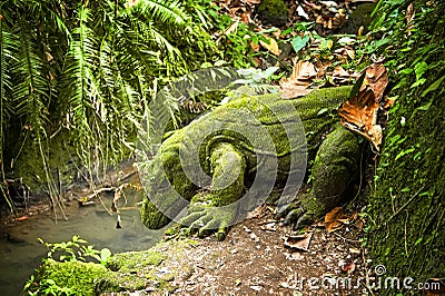 Dragon stone sculpture covered with moss in a rainforest Stock Photo