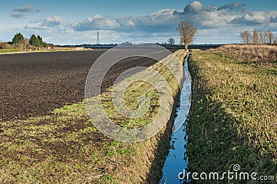 Drainage channel running alongside a ploughed field Stock Photo