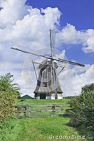 Drainage windmill with thatched roofing in a polder with dramatic shaped clouds and blue sky, Netherlands Stock Photo