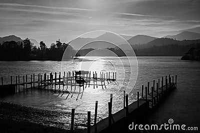 Dramatic Black And White Sunset At Derwentwater Lake In The Lake District With Haze Over Mountains. Stock Photo