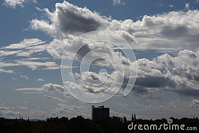 Dramatic clouds over the silhouette of a gas tank Stock Photo