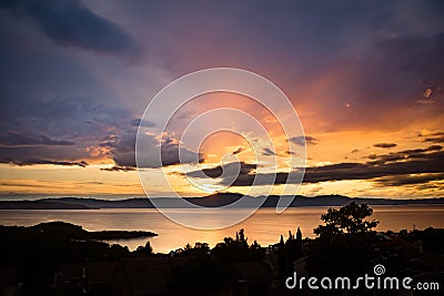 Dramatic and colorful sunset over Kvarner bay, with silhoueted trees in the foreground and the UÄka mountain Stock Photo