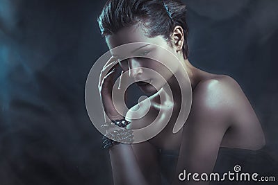 Dramatic dark portrait of young attractive woman in clouds of smoke Stock Photo