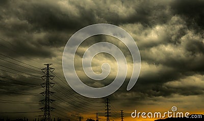Dramatic dark sky and clouds and high voltage pole with electric cable. Cloudy sky background. Black sky before thunder storm. Stock Photo