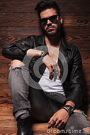 Dramatic fashion man in leather jacket and sunglasses sitting Stock Photo