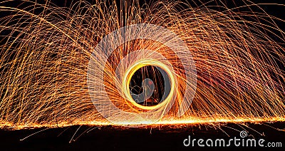 Dramatic glowing long exposure of spinning light trails with sparks Stock Photo