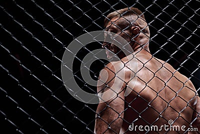 Dramatic image of a mixed martial arts fighter standing in an octagon cage. The concept of sports, boxing, martial arts Stock Photo