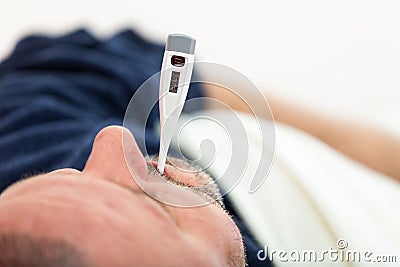 Dramatic image of a sick man laying in bed with fever Stock Photo