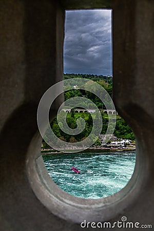 Dramatic Keyhole view of Rhein Rhine water fall in switzerland, background has green forest and dramatic cloudy sky Stock Photo