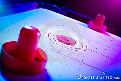 Dramatic lit air hockey table with puck and paddles Stock Photo