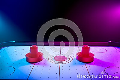 Dramatic lit air hockey table with puck and paddles Stock Photo