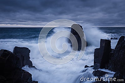 Dramatic nature background - big waves and dark rock in stormy sea, stormy weather. Dramatic scene. Stock Photo