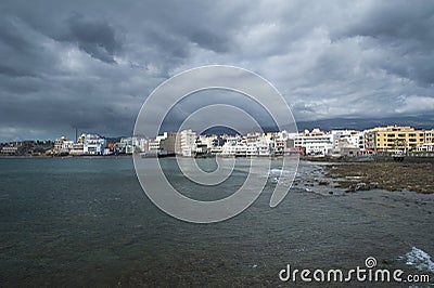 Dramatic overcast sky, low tide and calm waves in the town side of El Medano, Tenerife, Canary Islands, Spain Stock Photo