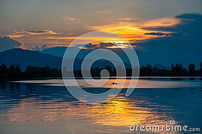 Dramatic panorama evening sky and clouds over mountain and lake at sunset Stock Photo
