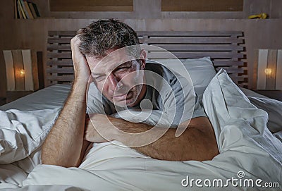 Dramatic portrait of young attractive sad and depressed man lying in bed crying desperate suffering depression problem and anxiety Stock Photo
