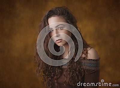 Dramatic portrait of a young beautiful brunette girl with long curly hair in the studio. Stock Photo