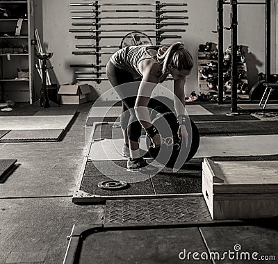 Dramatic shot of female weight lifter loading weights onto barbell Stock Photo