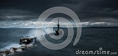 Dramatic shot of sea waves slamming against a jetty under a heavy cloudy sky Stock Photo