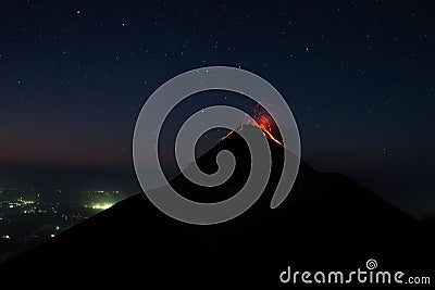 Dramatic shot of a volcanic eruption, with a cloud of ash and lava rising from the summit at night Stock Photo