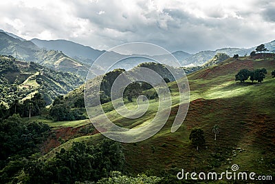 Dramatic image of sunlit mountains and hills of agricultural farms in Caribbean. Stock Photo