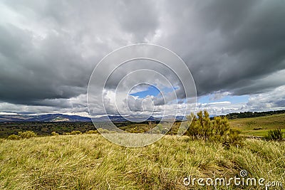 Dramatic sky of black clouds in the green field, wide angle view. Madrid Stock Photo