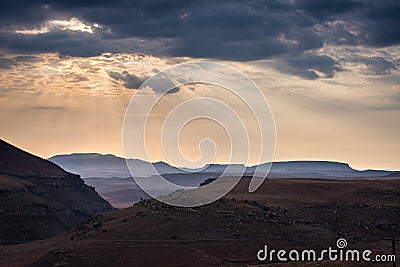 Dramatic sky, storm clouds and sun rays glowing over valleys, canyons and table mountains of the majestic Golden Gate Highlands Na Stock Photo