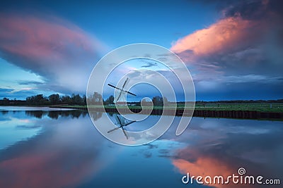 Dramatic stormy sunset over Dutch windmill and river Stock Photo