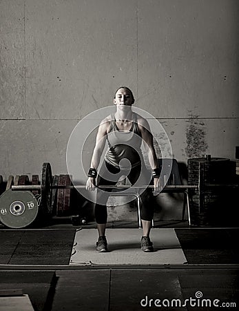 Dramatic subdued color image of strong female weight lifter with barbell Stock Photo