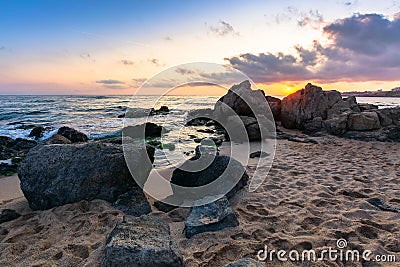 Waves crashing rocks on sandy beach. beautiful cloudscape above the horizon Stock Photo