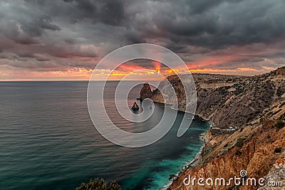 Dramatic sunset on cliffs seascape with the rays of the sun burning through menacing clouds, hdr cape Fiolent Crimea Stock Photo