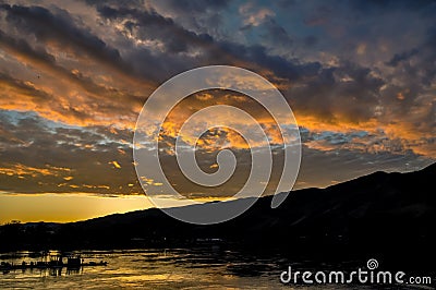 Dramatic sunset landscape with lake, sky reflection, fishing boat and foothills silhouette Snake River on the border of Idaho and Stock Photo