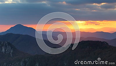 Dramatic sunset rays behind silhouette of of mountain Stock Photo