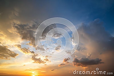 Dramatic sunset sky landscape with puffy clouds lit by orange setting sun and blue heavens Stock Photo