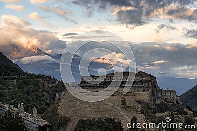 Dramatic view at Exilles Fort with high cloudy mountains on the Stock Photo