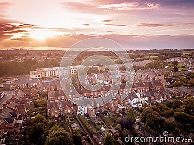 Sun setting with atmospheric effect over traditional British houses and tree lined streets. Stock Photo