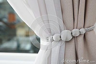 Draped window curtains with tieback in room Stock Photo