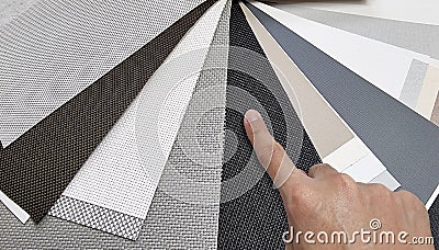 drapery catalog samples palette. architect's hand choosing samples of roller blind fabrics in different textures and colors. Stock Photo