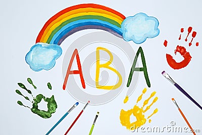 Drawn abbreviation ABA Applied behavior analysis, rainbow, palm prints and paintbrushes on white paper, flat lay Stock Photo