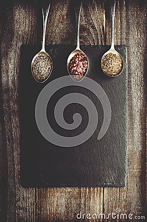 Dray spices on metal spoon on black stone with copy space. Wooden background. Chilli, pepper, marjoram. Stock Photo