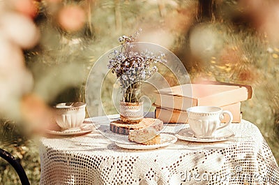 Dream like view through apple blossoms to table, set with tea cups and books. Stock Photo