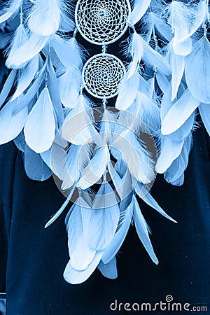 Dreamcatcher made of feathers, leather, beads, and ropes in classic blue trendy color of the year 2020 Stock Photo