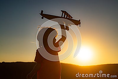 Dreaming kid. Boy pilot aviator with airplane. Dreams of traveling. Kids dream. Child on the background of sunset sky. Stock Photo